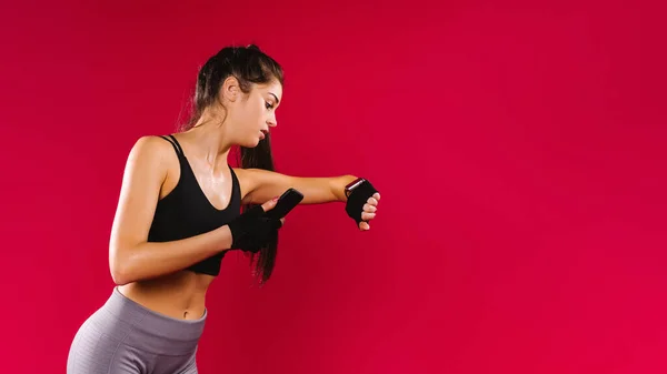 Banner. En flicka med en atletisk fysik i leggings och en topp, medan jogging, tittar på hennes resultat på en fitness klocka och delar resultatet med sina anhängare. Röd bakgrund med utrymme. — Stockfoto