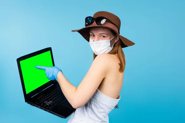 Летняя женщина в медицинской одноразовой маске, перчатки точки на рекламе, зеленый макет компьютера ПК, на пустом месте копирования для вашего рекламного текста, синий студийный фон — стоковое фото