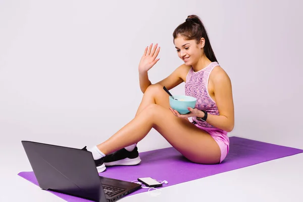 Młody bloger dyskutować w blogu wideo o zdrowym odżywianiu i fale uśmiecha się do swoich zwolenników przy aparacie na laptopa. Białe tło. — Zdjęcie stockowe