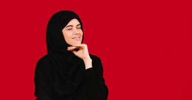 Banner, uzun format. Siyah tesettürlü güzel bir kadın kırmızı arka planda boş bir yan reklam alanı ile poz veriyor..