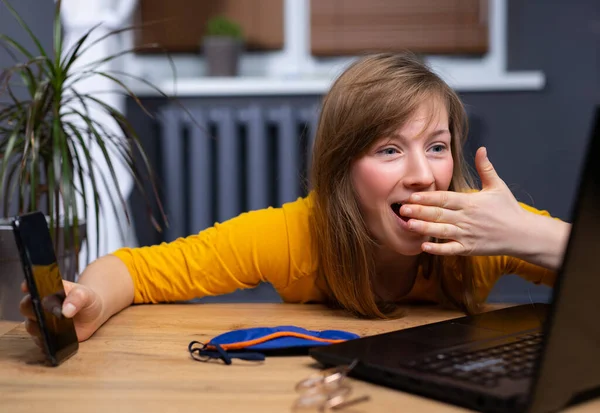 Bella donna bionda che utilizza laptop e smartphone su sfondo home office con mano sulla bocca. Maschera del sonno sul tavolo, viso scioccato e sorpresa. Successo, guadagno, paura, guadagni e sconvolto per errore. — Foto Stock