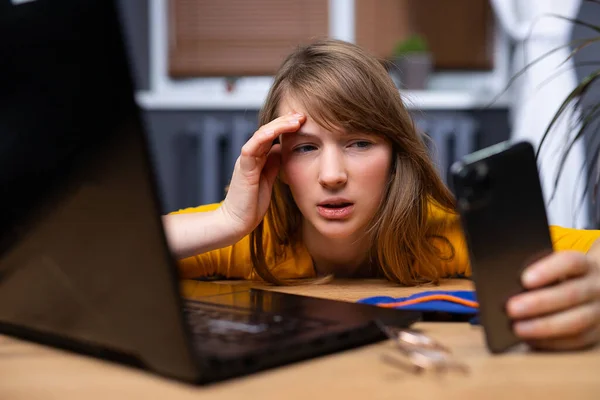 Una giovane ragazza assonnata è stanca dopo aver lavorato online e spegne l'allarme mattutino. Affaticamento e concetto di lavoro online. — Foto Stock