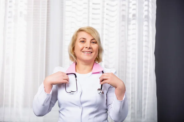 有听诊器的专业医疗经验 高级高加索女医生在医务室的镜头前笑容可亲 高质量的照片 — 图库照片
