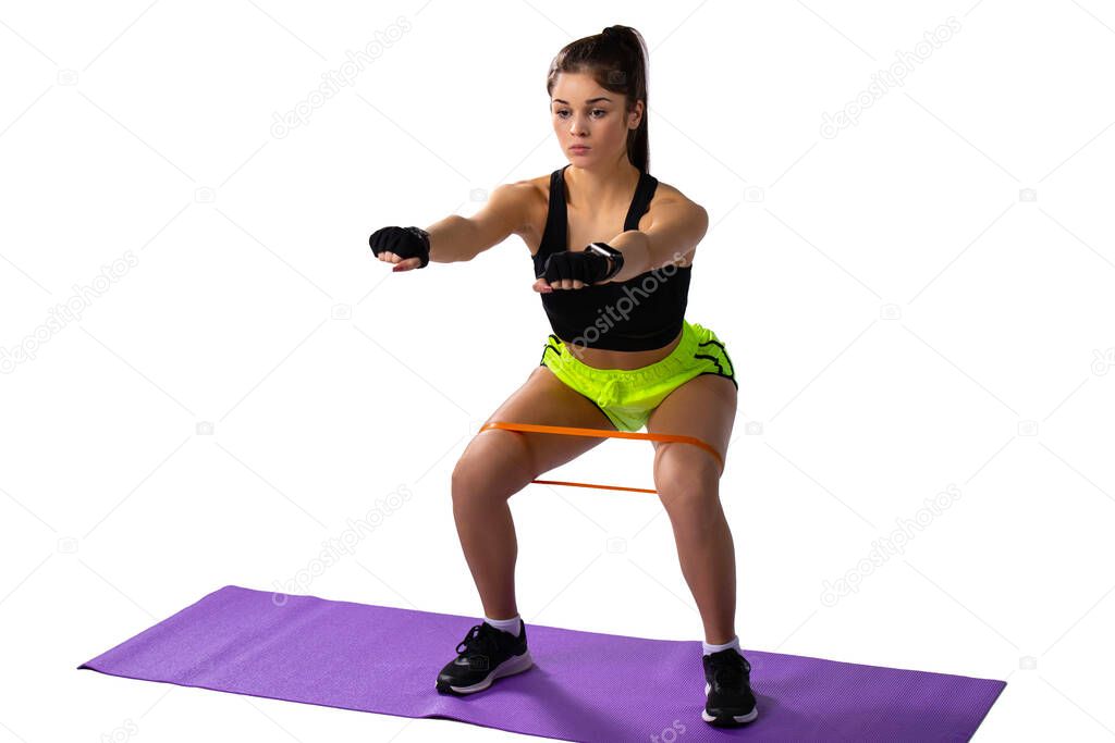 Fitness woman doing knee bends with resistance band on white background. Squatting sports girl. High quality photo
