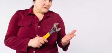 Banner, uzun format, gri arkaplan. Endüstriyel kadın yöneticinin İngiliz anahtarını gösteren portresi. Ciddi boyutta bir iş kadınının kameraya bakarken çekilmiş fotoğrafı.