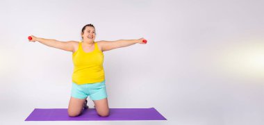 Banner, uzun format. Kilo vermek için halterlerle egzersiz yapan, gülümseyen şişman bir kadın. Reklam alanı olan arkaplan.