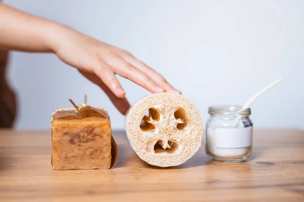 Female hand , fibrous sponge - luffa, natural laundry soap and baking soda in glass jar. Non-toxic house cleaning. Concept of green home. Template for the landing page for the eco cleaning service.
