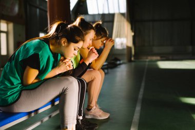 Oyuncular son golü beklerken başarı için dua ediyorlar. Spor kadınları, yedek bankta oturan spor salonunun sahasını kazanmak için takımlarıyla birlikte dua ediyor..