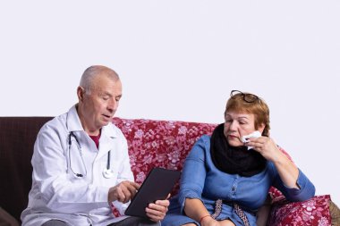 Erkek doktor danışmanlık yapıyor ve tıp bürosundaki yaşlı kadınla dijital tablet kullanarak bilgi topluyor. Yaşlı kadının hasta, sağlık sigortası ve ilacı var. Yüksek kalite fotoğraf