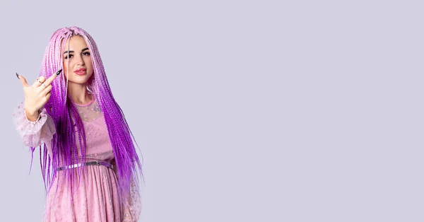 Banner, formato largo. Elegante mujer joven con grandes labios dulces y pelo largo rosa de pie y mostrando el dedo medio sobre fondo gris con mucho espacio lateral para la publicidad, info —  Fotos de Stock