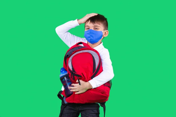 Maskeli bir çocuk. Elinde kırmızı renkli bir çanta, bir şişe su var. Alnına bir el koy. Coronavirus. Virüsü durdur.. — Stok fotoğraf