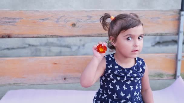 The little girl with two tails and blue dress hooking a beautiful flower on her head wants to be irresistible. — Stockvideo
