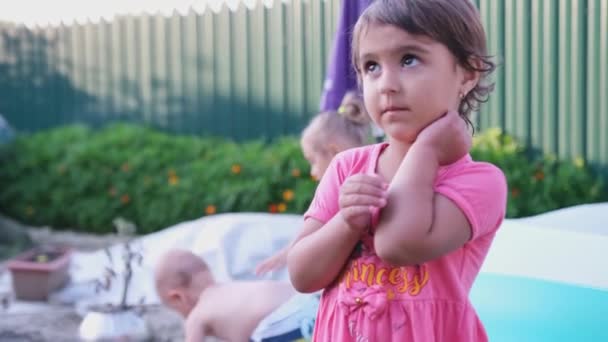 Ładna dziewczyna w różowej sukience pokazuje rękę upadła i czuje ból, ale uśmiecha się tak czy inaczej, jest odważna. — Wideo stockowe