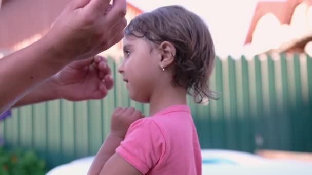 Papà è decora la testa della figlia con due fiori gialli e lei indossa una t-shirt rosa. — Video Stock