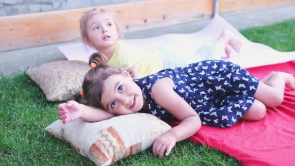 Tired cute caucasian kid girls are tired and they are laying down to rest on the bedspread and pillow. — Stok video