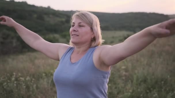 Cuore aperto donna sorridente taglio corto bionda in abiti comodi medita in natura nel campo all'aperto. — Video Stock