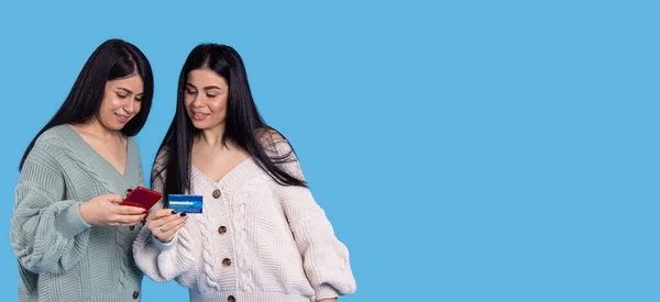 Banner, long format. Twins girls in knitted sweaters are holding cellphone and enter data from the card. — Φωτογραφία Αρχείου