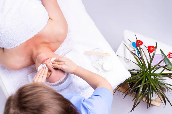 La foto di un cosmetologo in piedi che fa le procedure di ringiovanimento del viso usando tamponi di cotone bianco. — Foto Stock