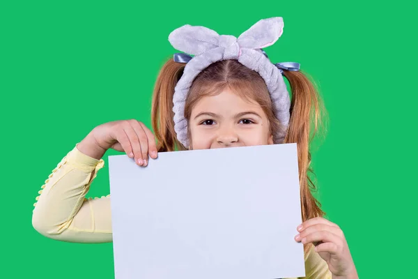 La niña sostiene el papel en sus manos cerrando la boca y en su cabeza hay un vendaje violeta, orejas. — Foto de Stock