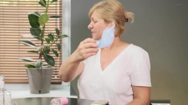 Tıbbi maskeyi çıkardığında yüzündeki sivilce ve tahriş sorununu gören bir kadının yüzü için endişelenen videoyu kapat..