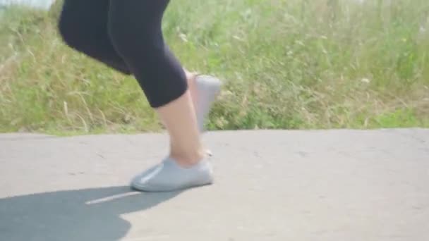 Κοντινό πλάνο βίντεο με τα πόδια της γυναίκας τζόκινγκ νωρίς το πρωί στο δασικό δρόμο, έννοια ενός υγιεινού τρόπου ζωής και τη διατήρηση του σώματος σε φόρμα. — Αρχείο Βίντεο