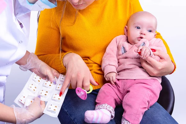 Madre sosteniendo a una linda niña con ropa rosa en sus rodillas eligiendo pendientes para su hija en el salón de belleza. — Foto de Stock