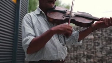 Yaşlı beyaz adam dışarıda keman çalıyor. Profesyonel olarak yay kullanıyor. Müziğini duyan herkese bir gün için harika bir ruh hali veriyor..
