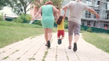 Arka planda, evli bir çiftin küçük kızını ellerinden tutup kaldırırken ve yolda birlikte koşarken videosu var..