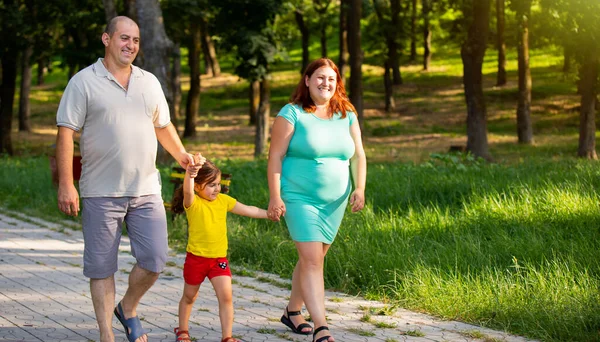 Όμορφη ωραία οικογένεια της υγείας των τριών περπάτημα μαζί στο πάρκο ξοδεύοντας το χρόνο είναι σε μια εξαιρετική διάθεση, χαμογελούν. — Φωτογραφία Αρχείου