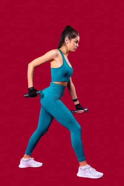 덤벨을 든 운동 여자의 프로필 사진에는 다리가 넓게 뻗어 있는 자세 운동을 하고 있는 날씬 한 몸에 꼭 맞는다. — 스톡 사진