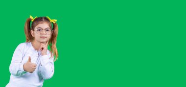 Beyaz bluzlu, gözlüklü küçük akıllı kız başparmağıyla hareket ediyor ve yanağına dokunuyor..