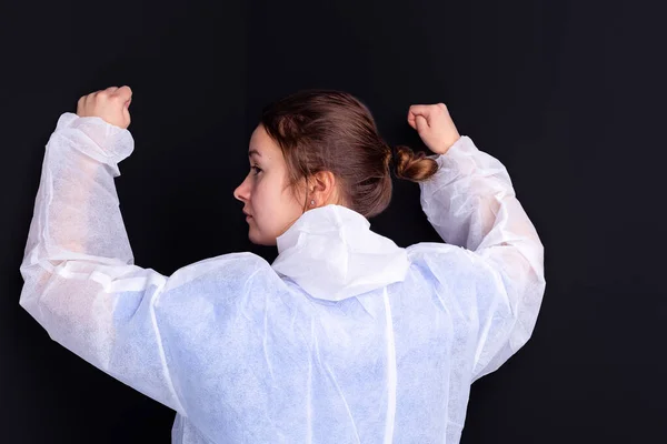 Enfermera médica con uniforme médico blanco levanta las manos con los puños cerrados posando de nuevo ante la cámara. —  Fotos de Stock