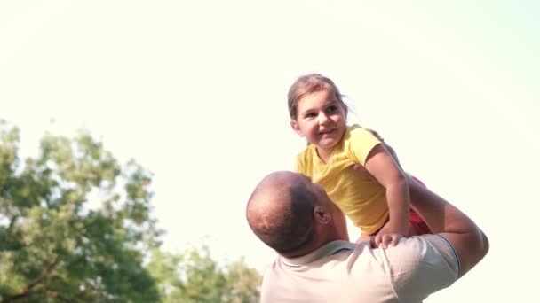 Loving father holding her little nice daughter in his hands and raises her overhead, little girl gave a kiss to her father, they are passing time together very good. — Video Stock