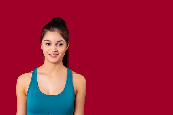 Fechar a foto de uma menina bonita sorridente posando na câmera vestindo top curto azul para exercícios de fitness. — Fotografia de Stock
