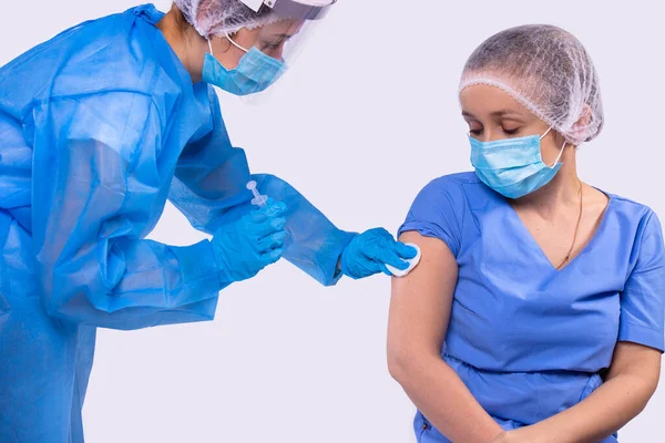 La doctora que usa jeringa inyecta a la enfermera joven usando una máscara y uniforme médico en el hospital.. — Foto de Stock