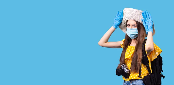 A menina de férias de verão usando o chapéu, mochila preta atrás e a câmera de foto na frente em máscara médica e luvas. — Fotografia de Stock