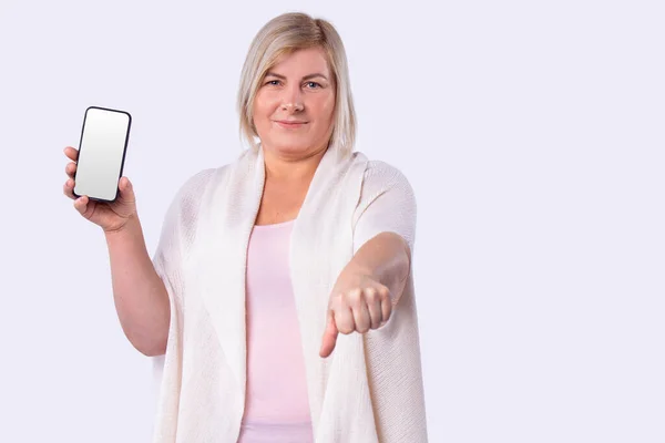 Donna sorridente tagliare i capelli biondi in un lungo cardigan bianco che tiene il telefono cellulare e raggiunto in un pugno. — Foto Stock