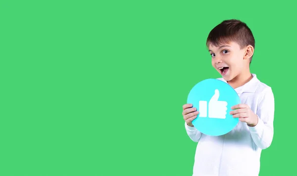 Niño con camisa blanca sostiene en sus brazos un papel, forma de círculo, color azul con un pulgar hacia arriba. — Foto de Stock