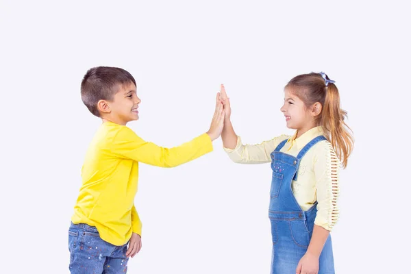 Dos adorables hermanos y hermanas dan los cinco primeros acceden a trabajar en equipo, de pie de lado y sonriendo. — Foto de Stock