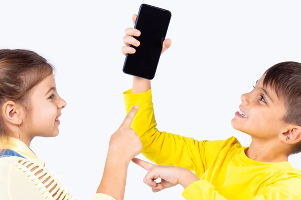 Dos niños agradable niño y niña luchando por el teléfono inteligente, el niño sosteniendo el teléfono en su mano y la chica quiere tomarlo . —  Fotos de Stock