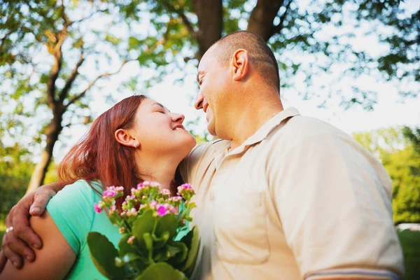 Felice coppia innamorata avendo appuntamento romantico all'aperto guardarsi e sorridere, l'uomo ha dato la sua donna ama i fiori e abbracciarla. — Foto Stock