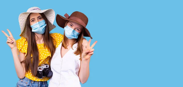 A foto de close-up de duas meninas em máscaras médicas ter a câmera fotográfica e fazer sinal de paz em tempo pandêmico. — Fotografia de Stock