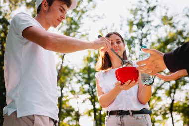 Bir çift gönüllü evsiz bir adama bir kase çorba ve plastik bir şişe su vererek yardım ediyor. Gönüllü görev kavramı..