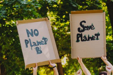 Gezegenimizi destekleyen, kirliliği ve küresel ısınmayı protesto eden iki karton pankartın fotoğrafını çek..