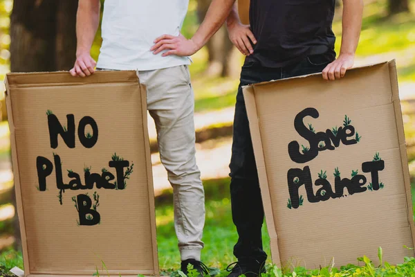 Обрізана фотографія двох чоловіків в чорно-білому одязі, що тримає картонні плакати з написом, щоб врятувати нашу планету і захистити її від забруднення . — стокове фото