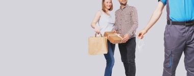 Elinde karton bir paket ve bir paket tutan genç ve güzel bir çiftin kesilmiş fotoğrafı. Elinde tıbbi maske tutan bir teslimatçı..