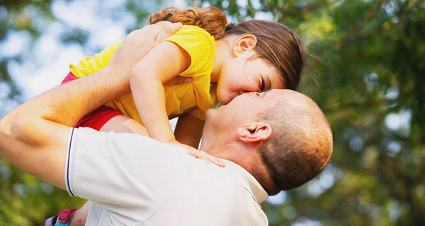 Κοντινές φωτογραφίες ενός μικρού κοριτσιού και του μπαμπά του, ο άντρας μεγάλωσε την κόρη του και δίνει ένα φιλί στο αξιαγάπητο κοριτσάκι της, περνάνε μια ωραία μέρα μαζί έξω.. — Φωτογραφία Αρχείου