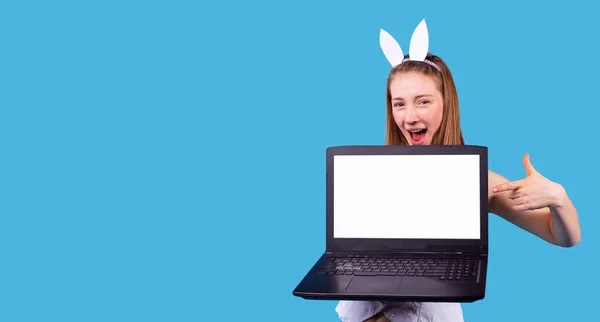 Sorridente ampia giovane donna che indossa il cerchio con le orecchie lepre tenendo il computer portatile aperto e indicando ad esso. — Foto Stock