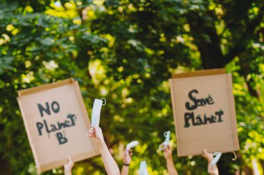 İklim değişikliğine karşı bir yürüyüş sırasında çevre aktivistleri tarafından tutulan ve salgın zamanında tıbbi maskeyi ellerinde tutan ev yapımı işaretlere yakından bakın..