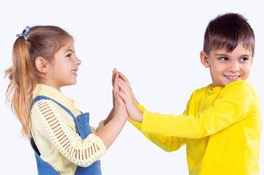 Avuçlarını birbirine değdiren iki sevimli çocuk ve oğlan tereddüt eder kız, başını sola çevirir..